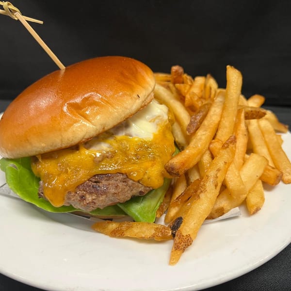 A Pasifika NW Grill & Bar cheeseburger with melted cheese and lettuce, served with golden fries.
