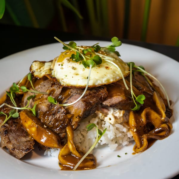 Pasifika NW Grill & Bar's Loco Moco with steak, gravy, fried egg, and microgreens over rice.
