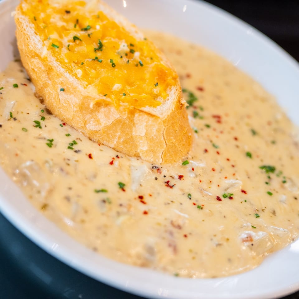 Creamy mushroom soup with a slice of toasted garlic bread, garnished with herbs and spices.